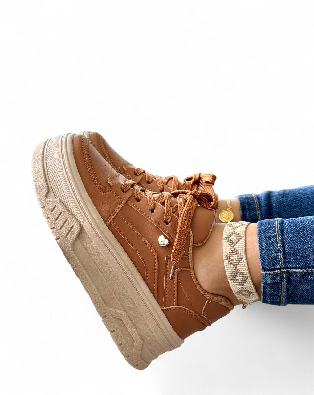 Brown sneaker with a thick sole worn by a person on a white background