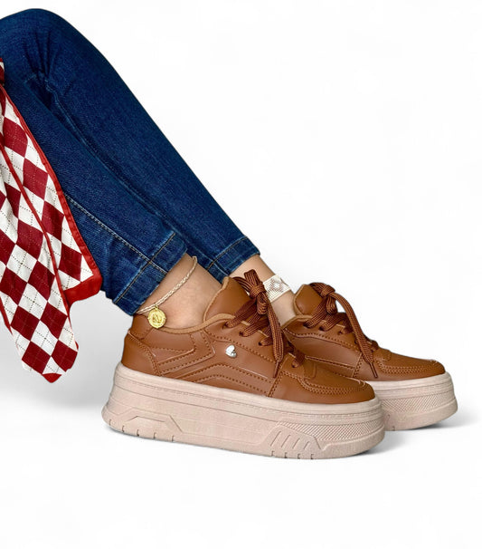 Brown platform sneakers worn with blue jeans and a red checkered fabric on a white background