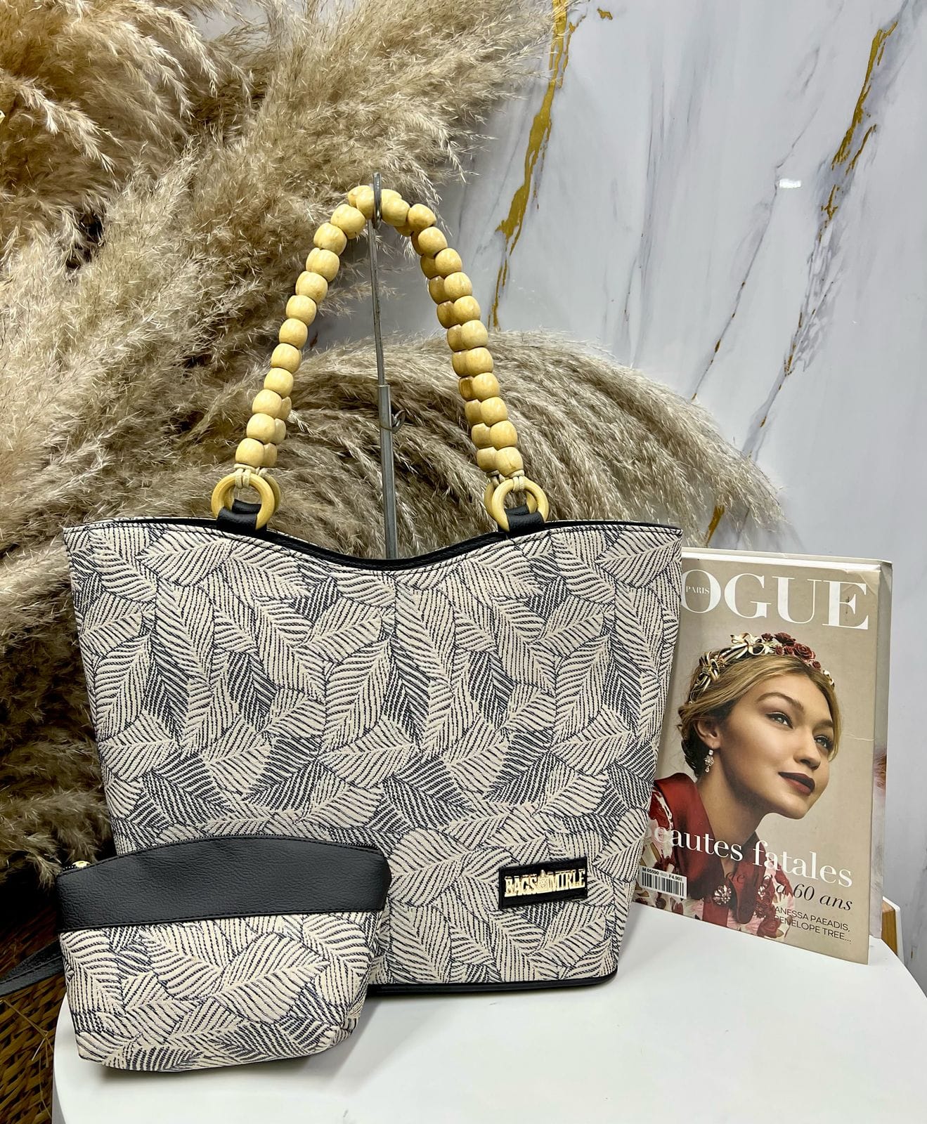 Patterned tote bag with wooden handle and matching pouch on a surface with a magazine in the background.