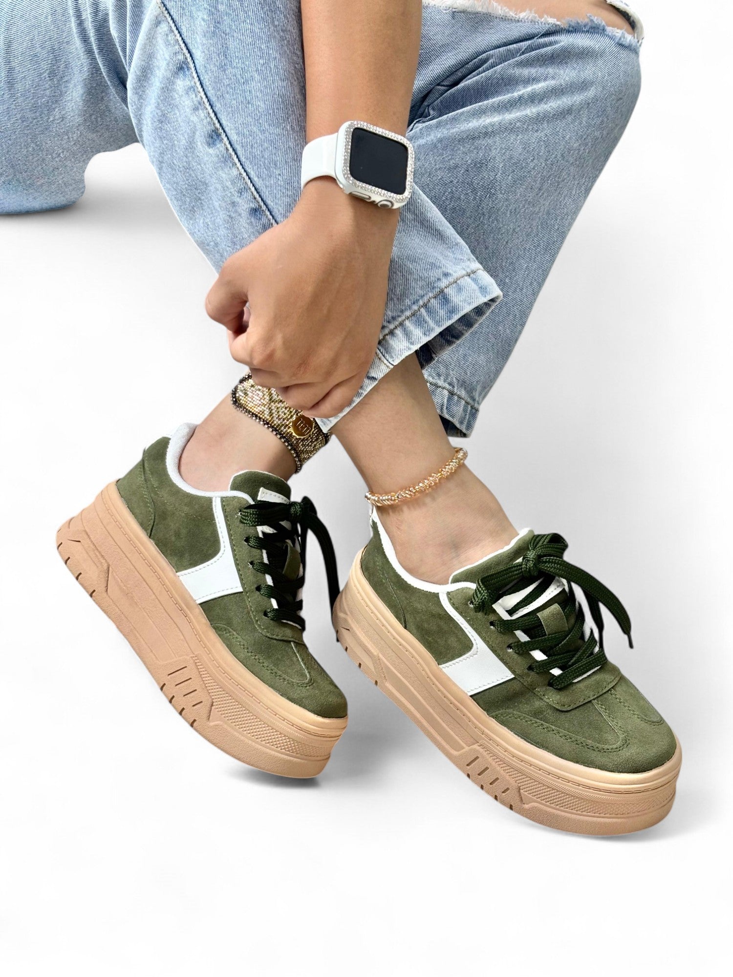 Person wearing green sneakers with brown soles on a white background