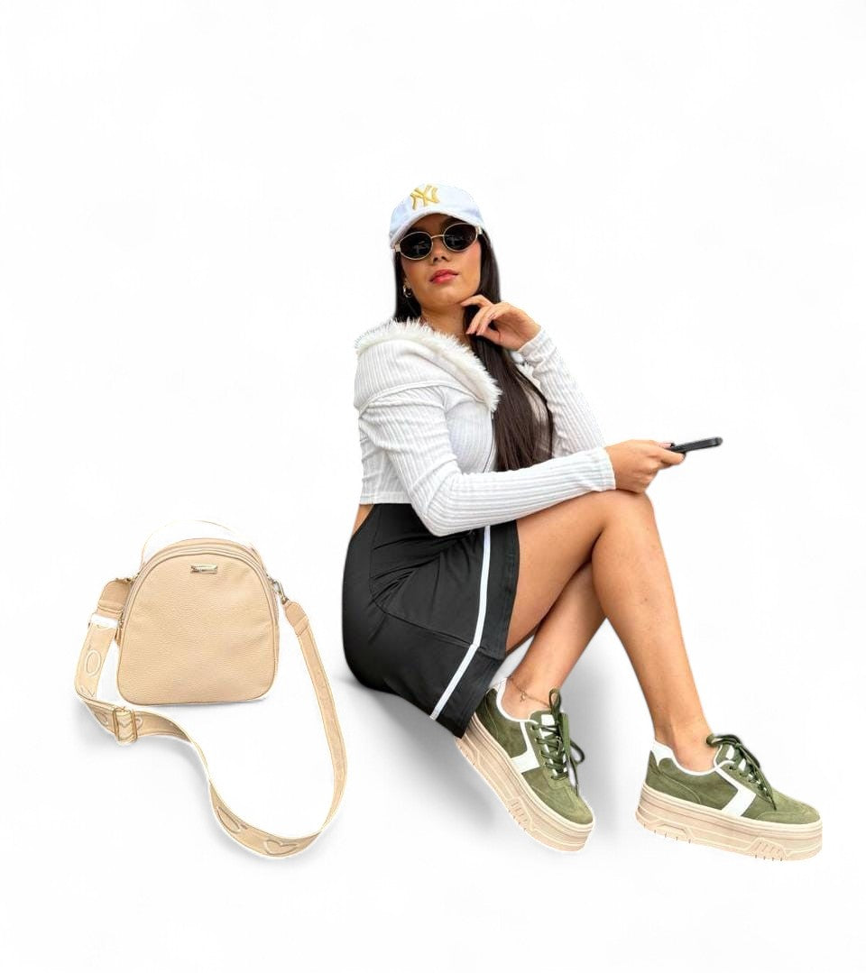 Woman sitting with a beige crossbody bag on a white background