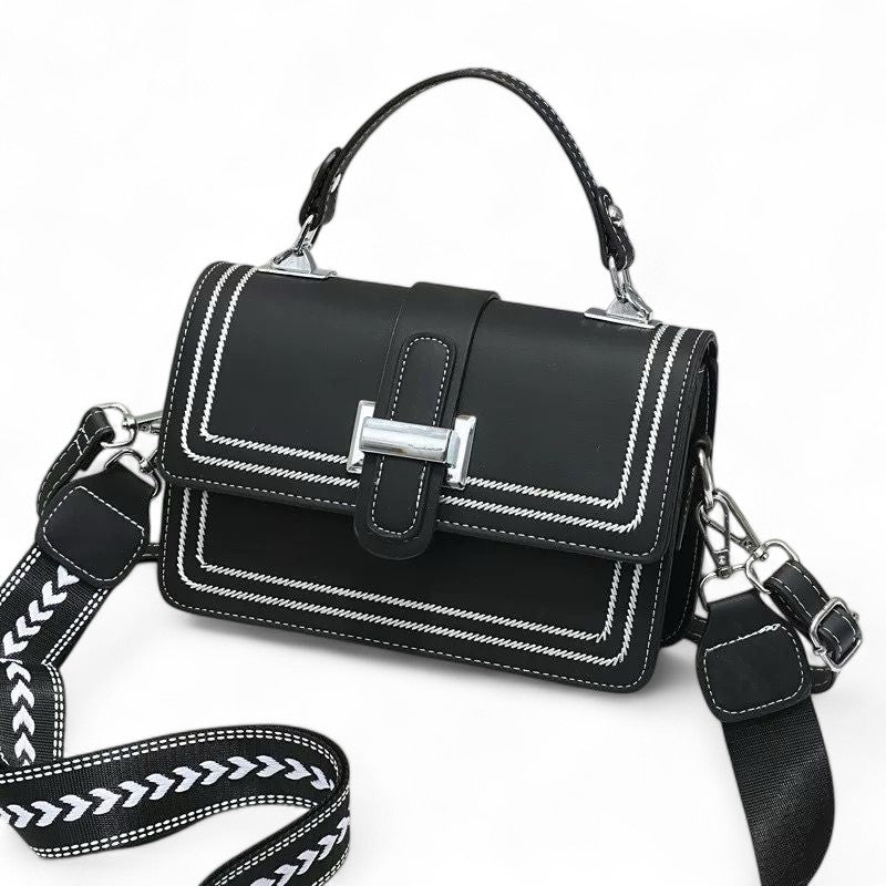 Black handbag with white stitching on a white background
