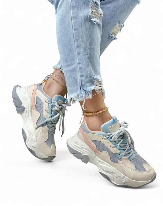 Beige and blue sneakers worn with ripped jeans on a white background
