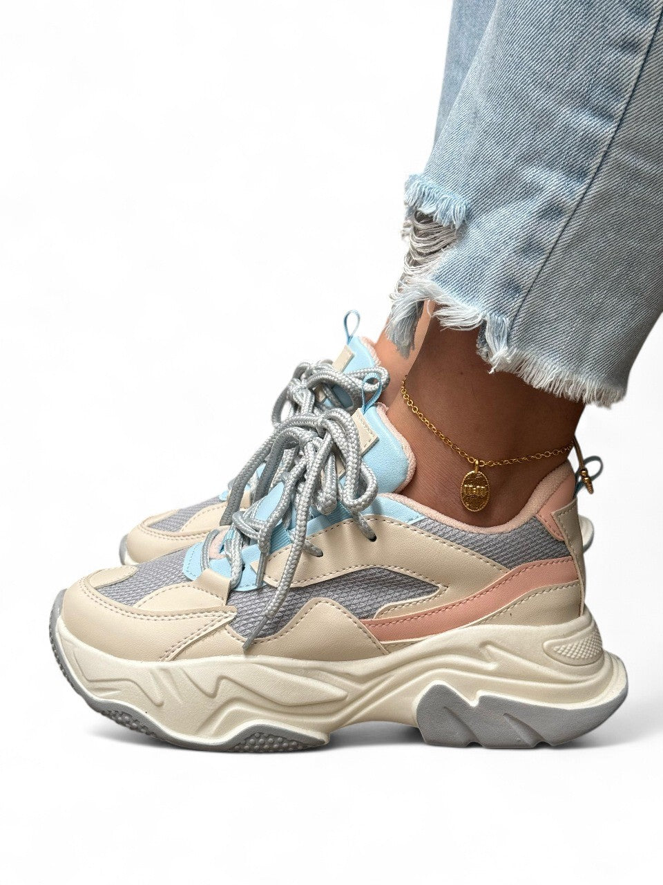 Beige and blue sneakers worn with ripped jeans on a white background